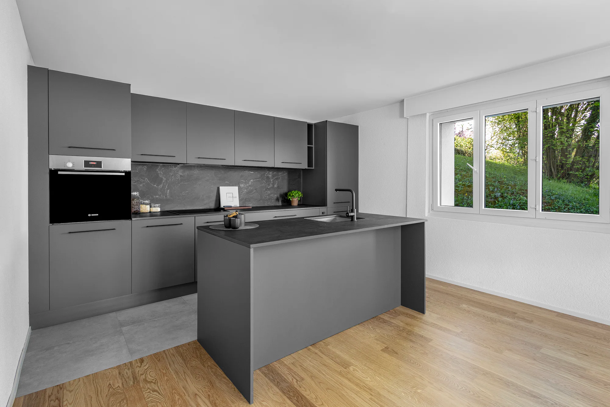 Cuisine graphite avec îlot réalisée par BP Cuisines dans une pièce lumineuse